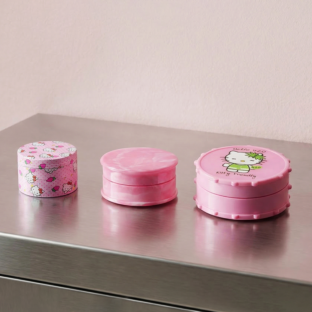 Three pink of BW Pink Plastic Weed Grinder 50mm Round in Strawberry Kitty design on white background, showcasing compact round grinder shape with Hello Kitty design on a metallic surface