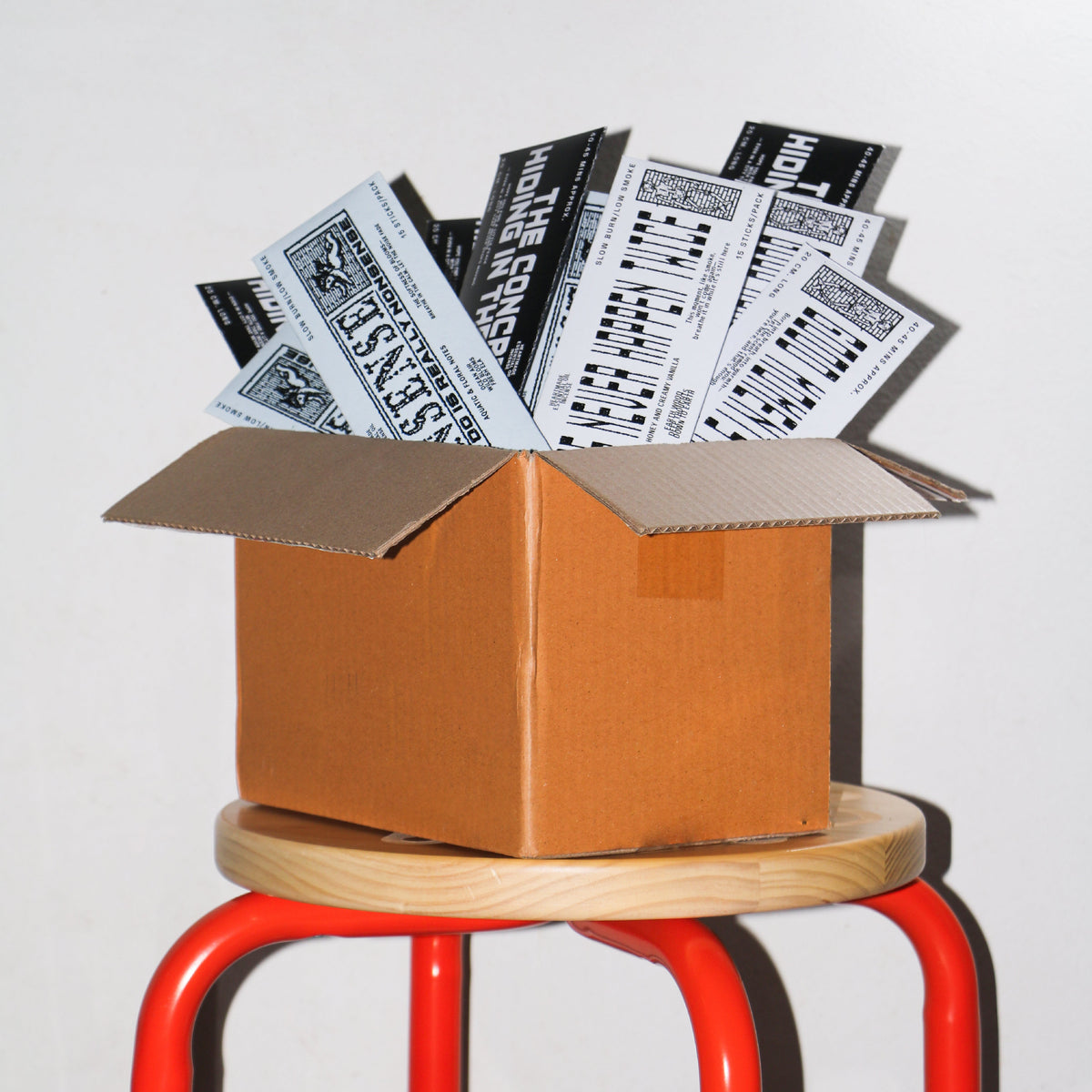 The Moment long stick incense packs in an open box on a stool | Bong Warehouse