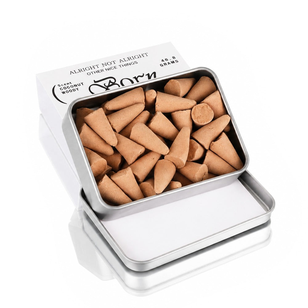 Open Alright Not Alright × SRHUB incense cones tin showing 50 cones inside, with paper sleeve packaging behind — apple, green note and sandalwood scent
