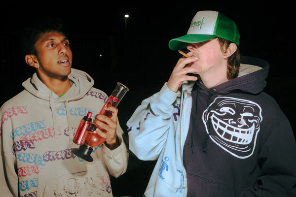 A Bong Warehouse Double Chamber 30cm Glass Bong – Pink Cherry Bomb and a person smoking a joint
