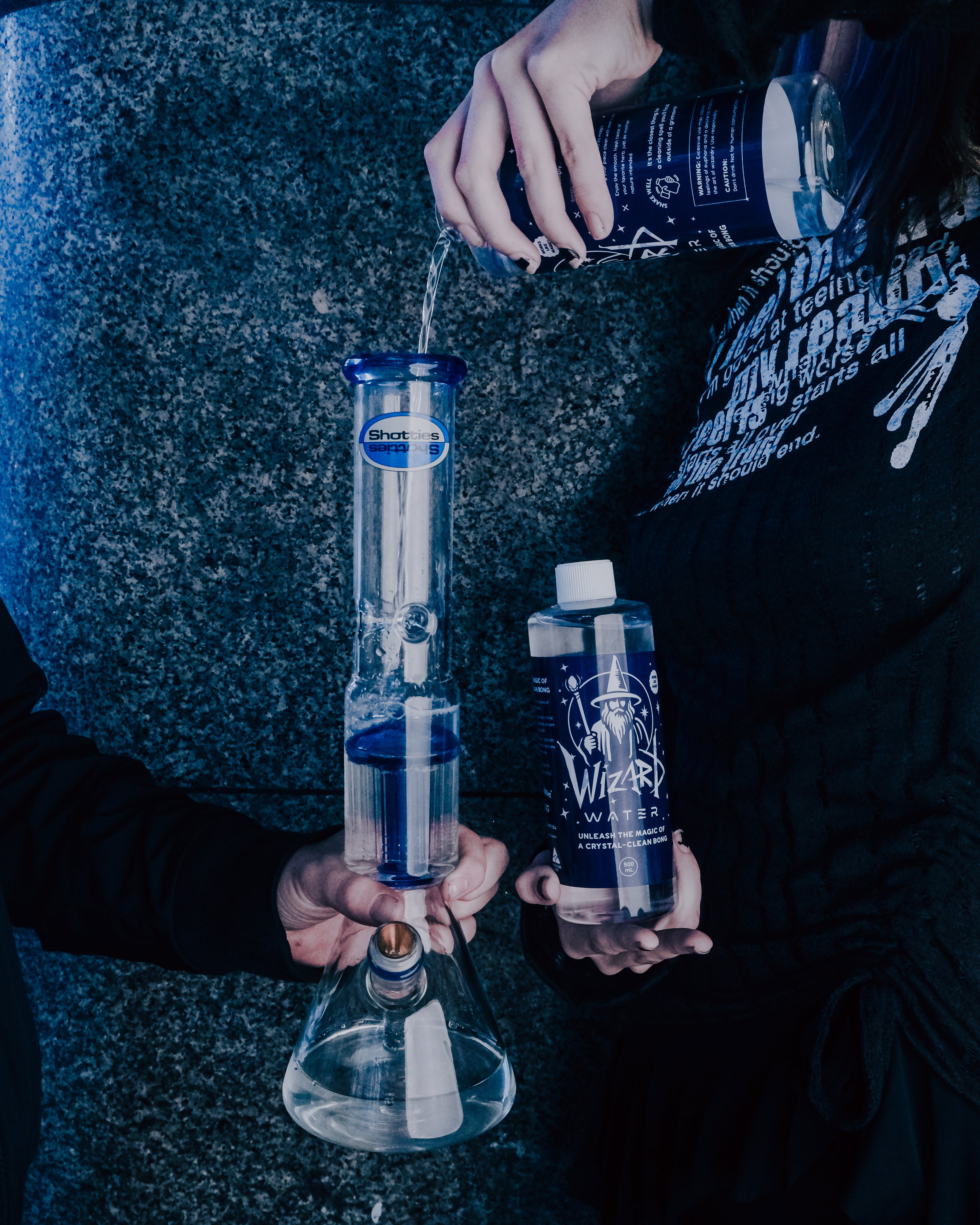 Pouring a bottle of Wizard Water into the Shotties™ 33 cm Glass Perc Pillar Bong in clear and blue glass from Bong Warehouse