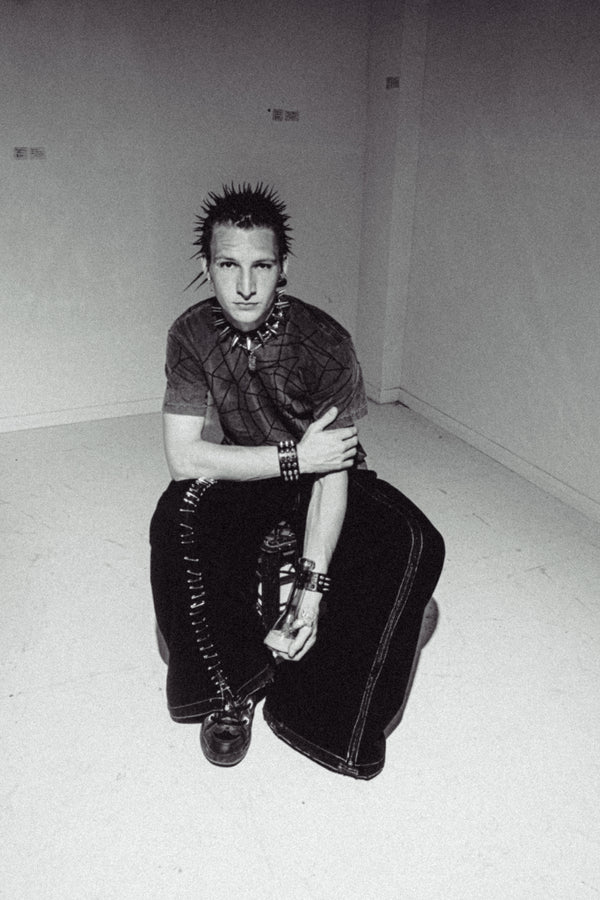 A man sitting on a crate and holding the Bong Warehouse Mini Beaker Bong in Purple