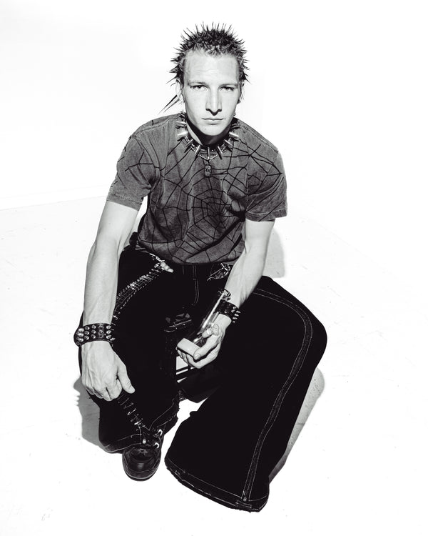Black and white photo of a man sitting on a chair with Bong Warehouse Mini Beaker Bong