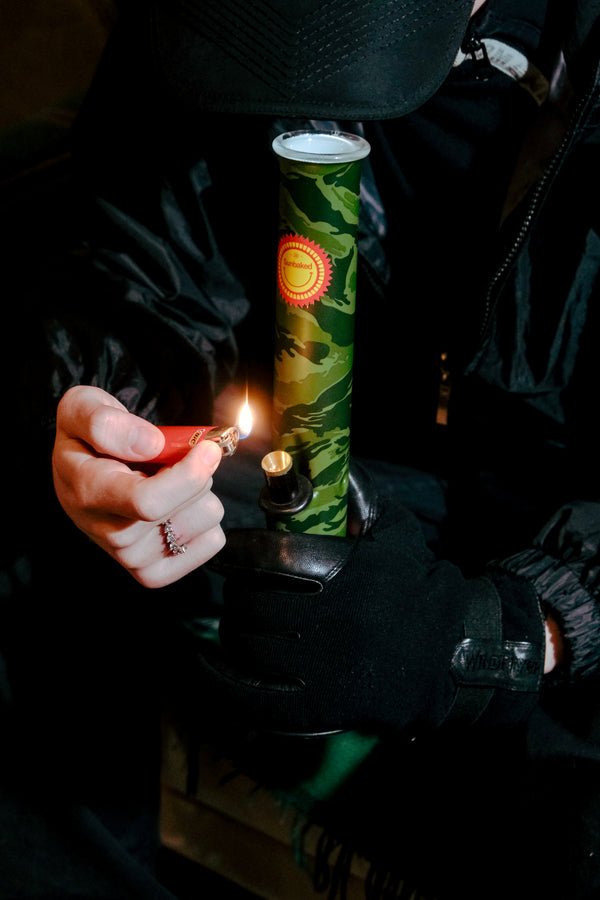 Fiddling with the lighter while smoking through the Bong Warehouse Large Tube 33 cm Glass Bong in Camo Sunbaked pattern