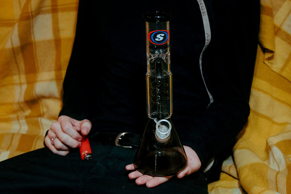 A lighter and a Shotties™ 30 cm Spiral Perk Glass Beaker Bong in clear and smokey glass from Bong Warehouse