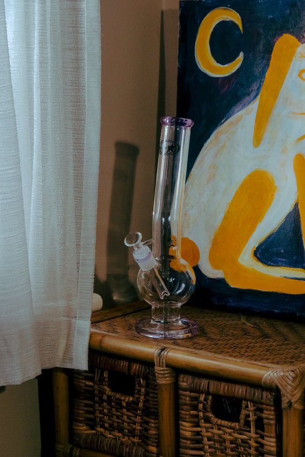 Shotties™ 33 cm Glass Bent Bubble Bong in clear and purple glass from Bong Warehouse, displayed on a drawer