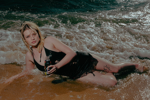 Woman lying on beach with Bong Warehouse Black High Tiger Mini Bottle in hand.