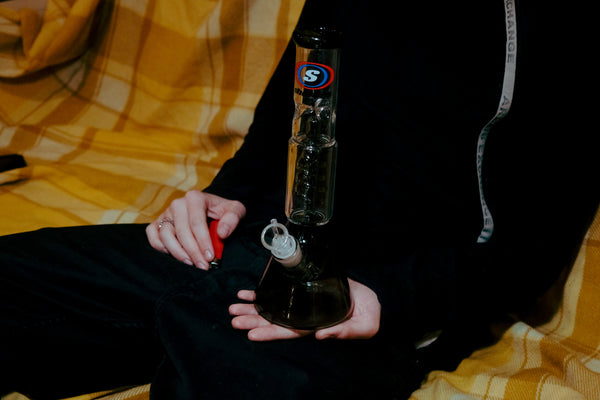 A man with a lighter holding the Shotties™ - 30cm Spiral Perk Glass Beaker Bong  in Clear Smokey Glass from Bong Warehouse
