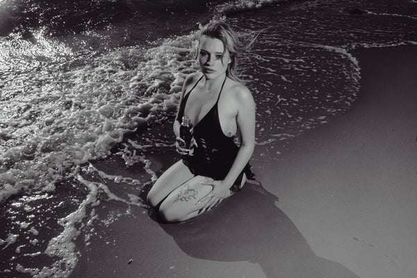 Woman seductively seated with little waves, holding Bong Warehouse Black High Tiger 17.5cm Bottle Bong