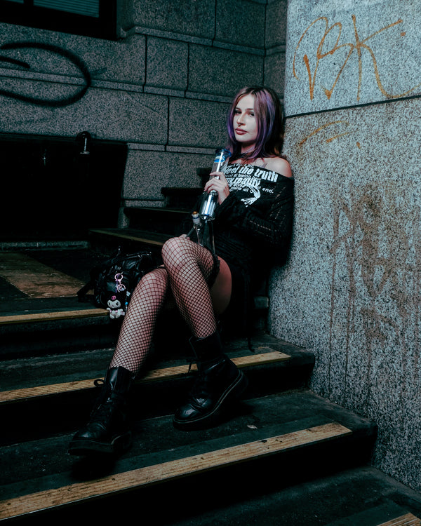Sitting and smoking on a stairway through a Shotties™ 33 cm Glass Perc Pillar Bong in clear and blue glass from Bong Warehouse