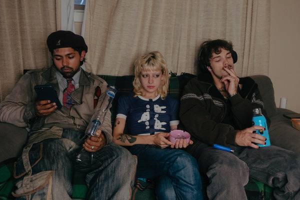 Three people sitting on a couch, each holding a Shotties™ - 40cm Glass Multi Arm Perc Beaker Bong - Clear/Blue  from Bong Warehouse