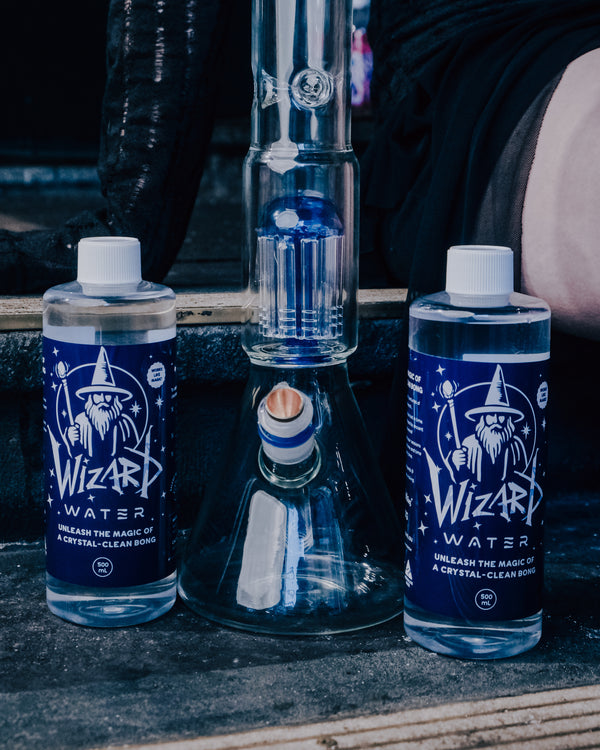 Shotties™ 33 cm Glass Perc Pillar Bong in clear and blue glass from Bong Warehouse with bottles of Wizard Water