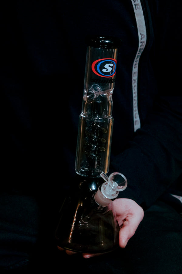 Shotties™ 30 cm Spiral Perk Glass Beaker Bong in clear smokey glass from Bong Warehouse, steady on a palm