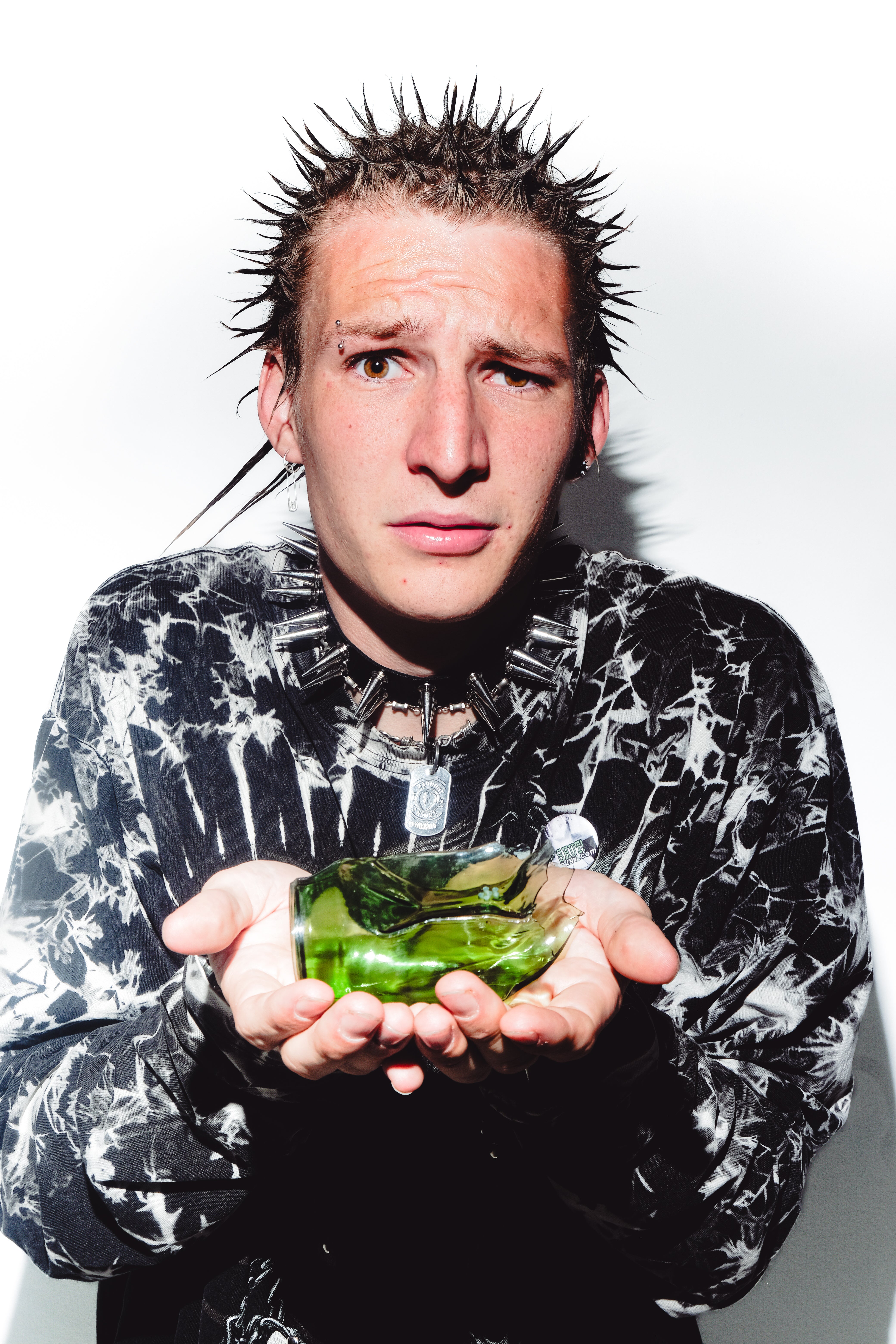 A confused man with the green shattered Bong Warehouse Cute Soda Can Glass Bong resting on his palm