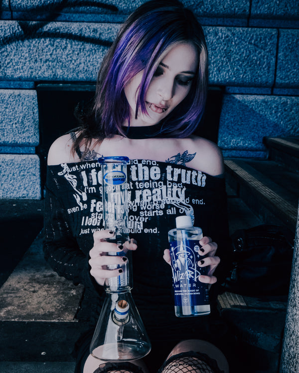 A woman holding a Shotties™ 33 cm Glass Perc Pillar Bong in clear and blue glass from Bong Warehouse and Wizard Water